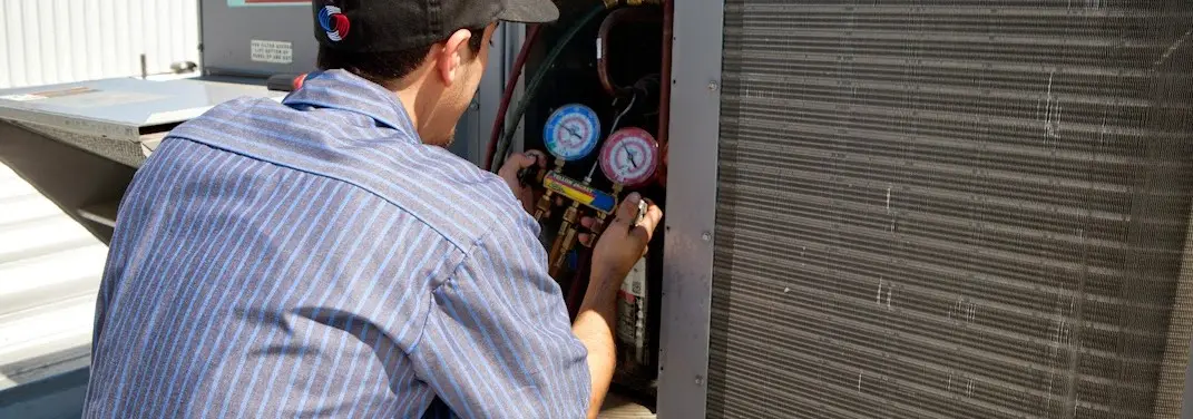 HVAC technician servicing a condenser unit in Bellwood